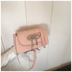 Detailed macro view of pink suede mini bag featuring a sparkling rhinestone bow buckle
