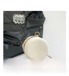 Macro detail of white marble pattern round crossbody bag with gold chain and clasp
