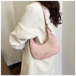 Detailed side view of pink crescent shoulder bag with pleated texture and adjustable strap
