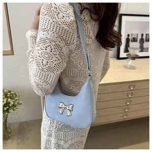 Pale blue faux suede underarm bag with a silver metal bow worn with a white crochet top