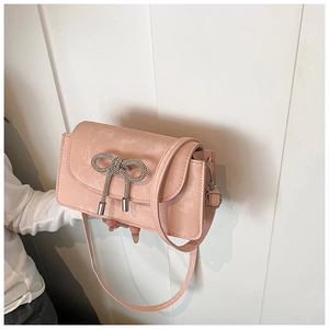 Detailed view of pink crossbody bag with sparkling rhinestone bow and leather texture