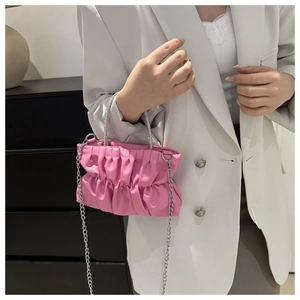 Detailed view of pink pleated handbag with rhinestone handle and silver chain strap