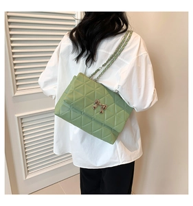 Détail du sac matelassé en similicuir vert clair avec nœud argenté et bandoulière