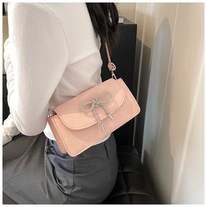 Detail of light pink faux leather bag featuring a large silver rhinestone bow ornament