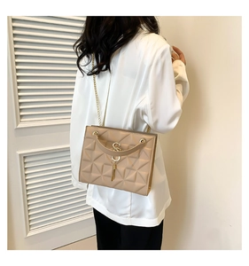 Detail of beige quilted crossbody bag with golden chain strap and fringe tassel