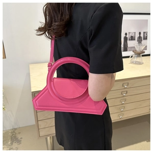 Borsa magenta con manico rotondo indossata da modella in abito nero