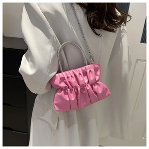 Detail of pink pleated bag featuring a rhinestone top handle and silver chain strap