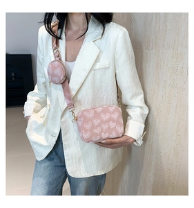 Close-up of a pink heart-printed crossbody camera bag with a detachable coin purse detail
