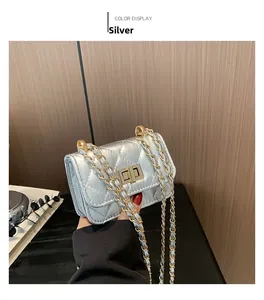 Close-up of silver quilted crossbody bag featuring a gold turn-lock and metal chain strap
