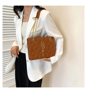 Close-up of brown quilted crossbody bag with gold metal S logo and fringe detail