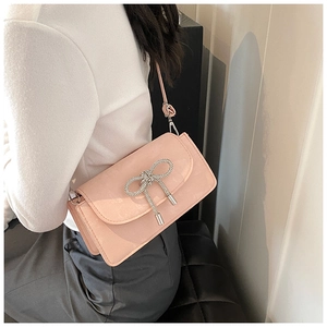 Close-up of pink crossbody bag featuring a sparkling silver rhinestone bow decoration
