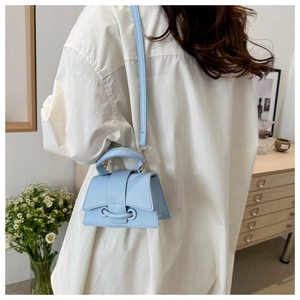 Dettaglio della mini borsa in pelle martellata azzurra con finiture dorate su modella