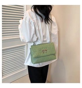 Détail du sac bandoulière vert matelassé avec fermoir papillon argenté et chaîne