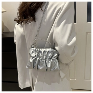 Detail of silver pleated crossbody bag featuring a rhinestone-encrusted handle and chain