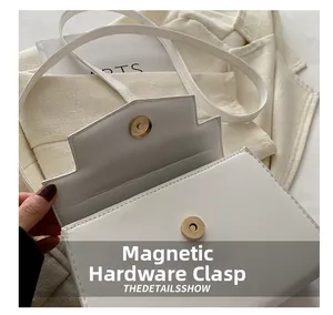 Dettaglio della chiusura magnetica in metallo sulla b flap della borsa Kelly in pelle bianca