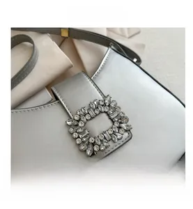 Détail macro du sac à main en cuir argenté métallisé avec boucle en strass étincelante