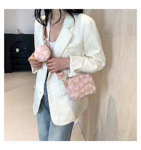 Detail of pink crossbody bag set with white heart patterns and wide shoulder strap