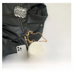 Close-up of white marble pattern round bag with gold metal chain and hardware details