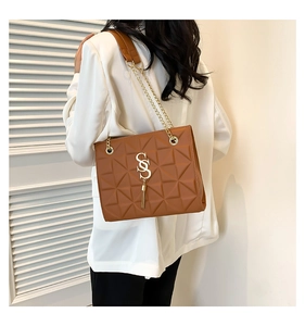 Detail of a brown quilted leather shoulder bag with gold metal logo and chain strap