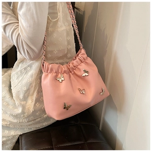 Detailansicht der rosa Beuteltasche mit Metallschmetterlingen und Lederkettenriemen