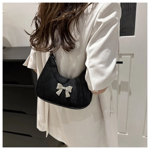 Detail of black crescent hobo bag with large silver metal bow accent and smooth texture