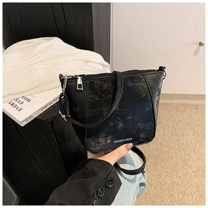 Dettaglio della borsa a tracolla nera con trama opaca e scritta Fashion Bags incisa