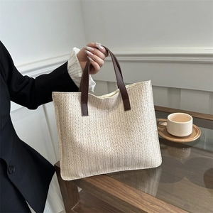 Minimalist beige woven tote bag with dark brown leather handles for daily commute style