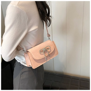 Detail of pink suede crossbody bag featuring a sparkling crystal bow decoration