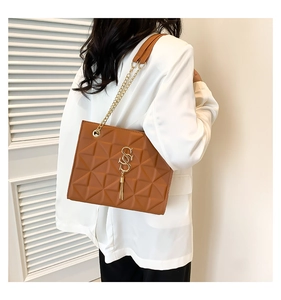 Detail of caramel shoulder bag with geometric quilting, gold logo and chain strap
