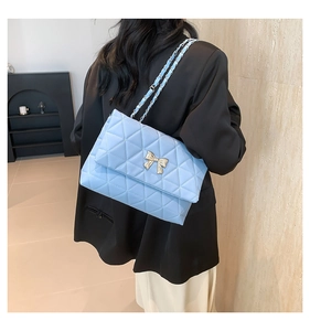 Détail du sac à bandoulière matelassé bleu clair avec boucle papillon dorée chic