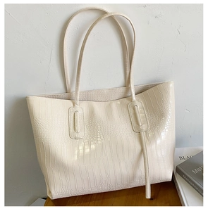 Détail du sac cabas crème effet croco avec doubles bandoulières sur une table en bois