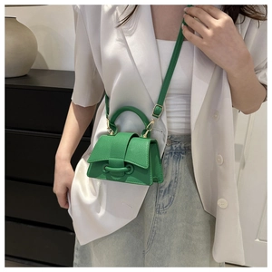 Dettaglio della mini borsa a tracolla in pelle verde abbinata a un blazer bianco