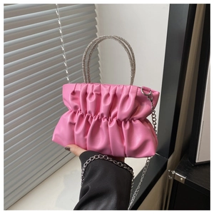Detail of pink pleated handbag featuring a rhinestone handle and silver chain strap