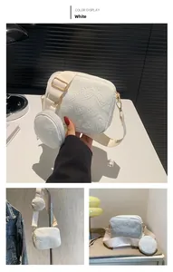 White heart-embossed crossbody bag detail featuring a round coin purse and gold buckle