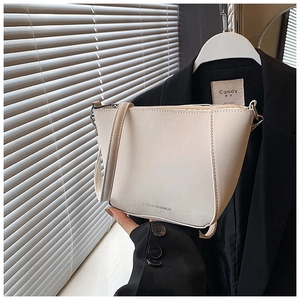 Dettaglio della borsa a secchiello in pelle PU crema con scritte fashion e zip metallica