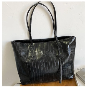Gros plan détaillé d'un sac cabas noir à texture crocodile montrant le grain du cuir