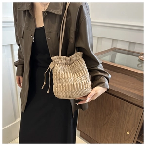 Détail du sac seau plissé beige avec un design texturé et fermeture à cordon