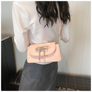 Detail of pink crossbody bag featuring a silver rhinestone bow with a soft matte finish