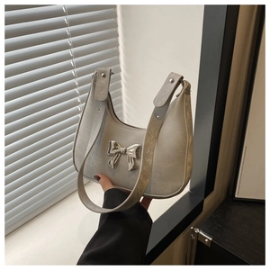 Detail of silver crescent shoulder bag featuring vintage crackle texture and metal bow