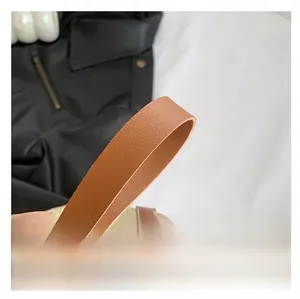 Macro shot of durable brown litchi pattern leather shoulder strap on straw tote bag