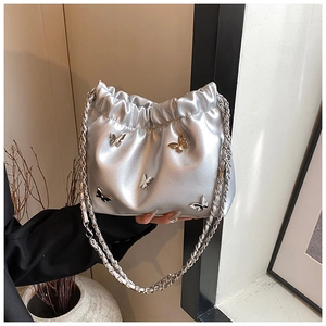 Detail der silbernen Metallic-Eimertasche mit 3D-Schmetterlingen und Kettenriemen