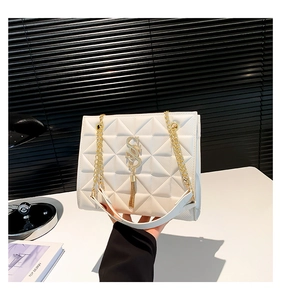Detail of white quilted handbag featuring gold metal chain strap and 'S' logo hardware
