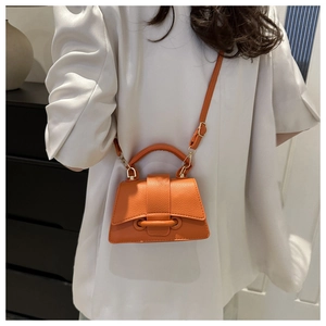Borsa a tracolla arancione brillante con trama litchi su modella in blazer bianco