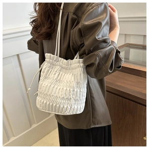 Detail of white drawstring bucket bag featuring pleated texture and minimalist design