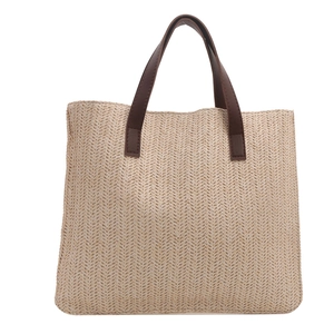 Detailed herringbone weave of beige straw tote bag with brown faux leather handles
