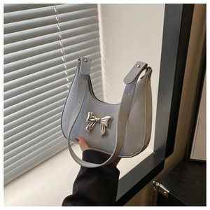 Close-up of light blue half-moon bag with silver metallic bow and adjustable strap