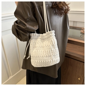 Détail d'un sac seau blanc à cordon avec texture plissée élégante sur un mannequin