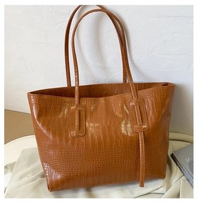 Détail d'un sac cabas marron à motif crocodile avec texture brillante et fines anses