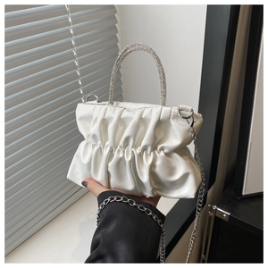 Detail of white pleated handbag with rhinestone-encrusted handle and silver chain