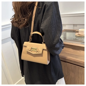 Detail of beige PU leather bag with golden metal chain strap in lifestyle setting